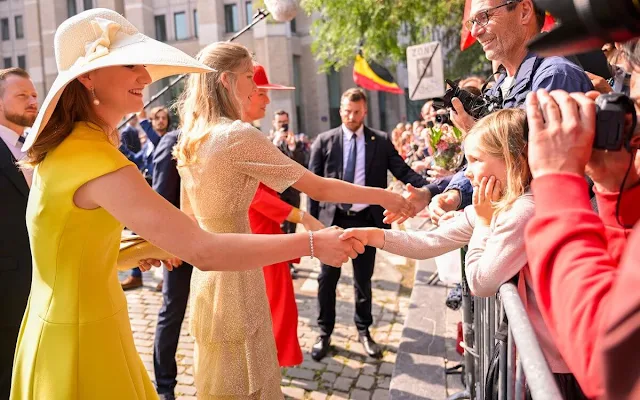 Princess Eleonore wore a ruffled midi dress by Maje. Princess Elisabeth wore a yellow dress. Queen Mathilde wore a red dress