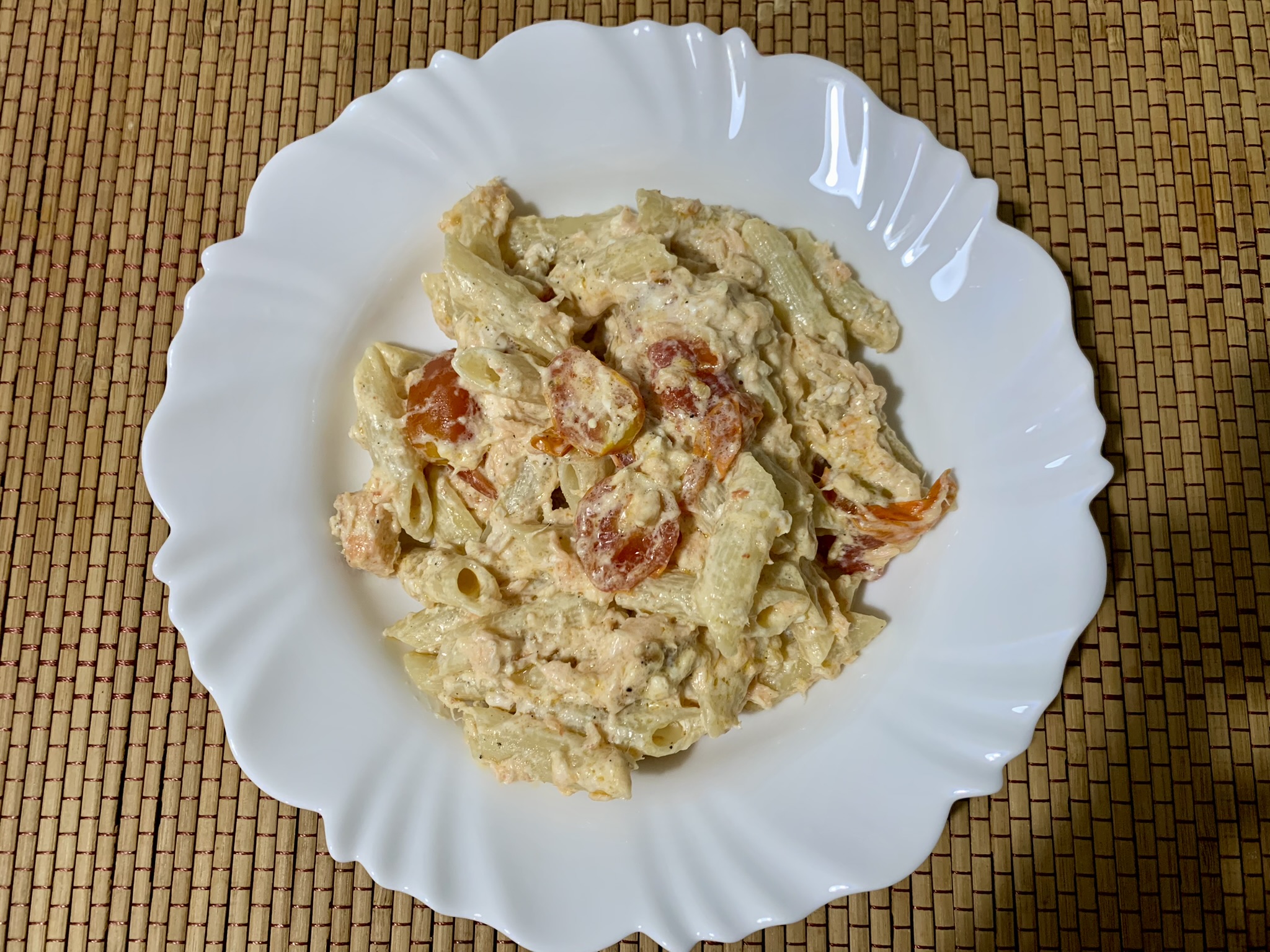 Penne com Salmão, Tomate Cereja e Cream Cheese Light em prato branco em cima de jogo americano em madeira