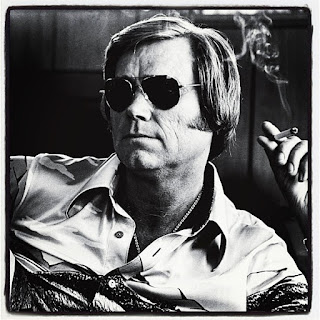 Photo of Country music singer George Jones wearing sunglasses and holding a cigarette.