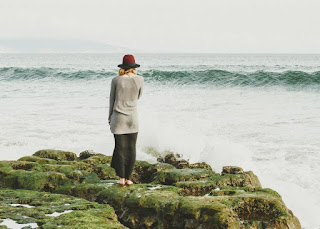 Femme sur un rocher au bord de la mer