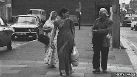 Indian women wearing saris walking down the road alongside a white man 
