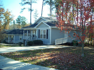 Blue and white Habitat home with a driveway and ramp built on a slope