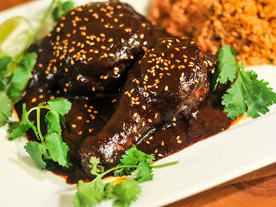 Un plato de mole poblano casero con arroz blanco, pollo y tortillas de maíz, listo para disfrutar de su sabor auténtico y delicioso