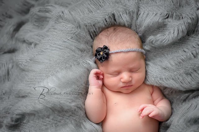 head shot of cute newborn baby lying on grey blanket