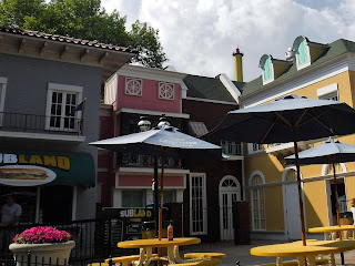 a sandwich restaurant with patio tables and umbrellas at Adventureland in Altoona Iowa