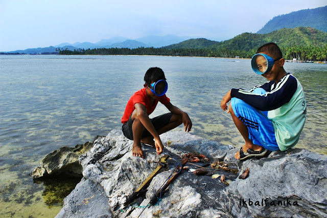 Dua bocah saat mendemontrasikan hasil ikan tangkapan dengan cara menyelam menggunakan perlatan terbuat dari besi behel dan kayu.