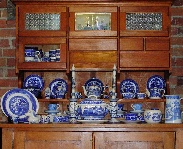 An old kitchen cupboard with Hoosier Top displaying a collection of Blue Willow china.