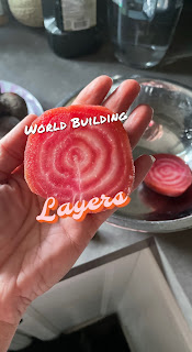 a hand holding a chioggia beet sliced in half showing the red and white alternating rings and the words World Building Layers around it