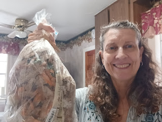 Image of smiling woman holding a clear plastic bag filled with vegetable scraps.