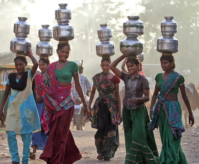 Women collect waterfrom a well.A rural life involves much contact with the elements.