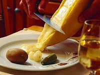 A heated section of Raclette cheese being scraped on to a plate.