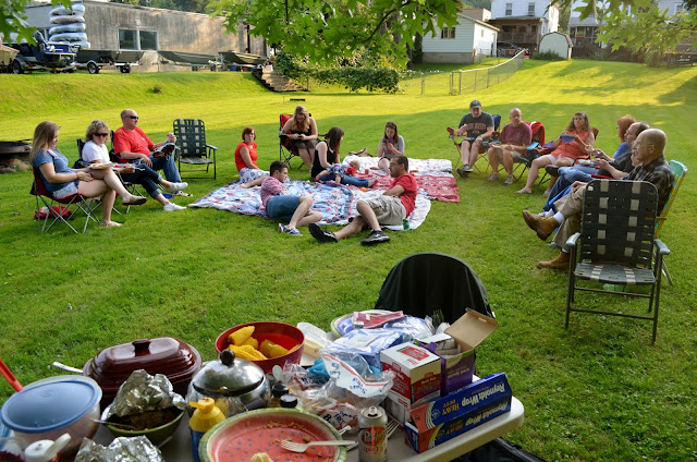 fourth of july picnic with big table of food and people sitting on blankets