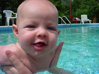 Image of a happy baby being held just out of the pool water: This article is about Water Discovery Games and Songs 