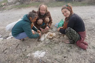 3 people squatting cracking nuts