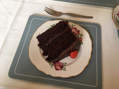 Slice of chocolate cake with a half-strawberry, on a plate with a cake fork
