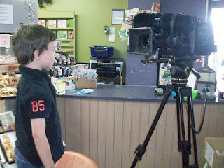 Xavier standing a chair looking through the tv camera