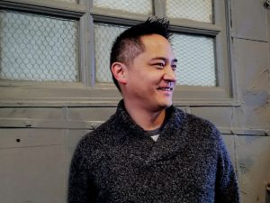 Author Mike Chen wearing a cozy sweater and looking off to the side.