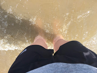 My legs standing in the water.