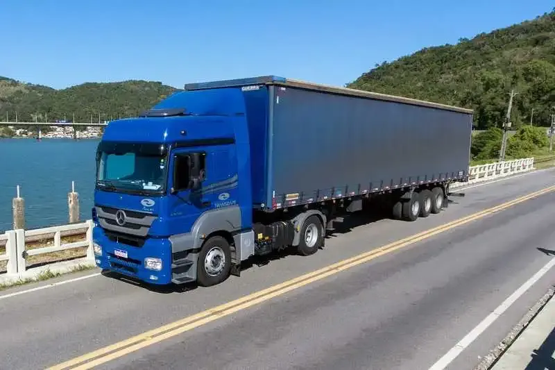 Mercedes-Benz Axor azul e carreta sider azul em ponte sobre rio