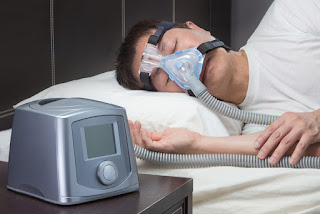 A man sleeping with a breathing apparatus on. 