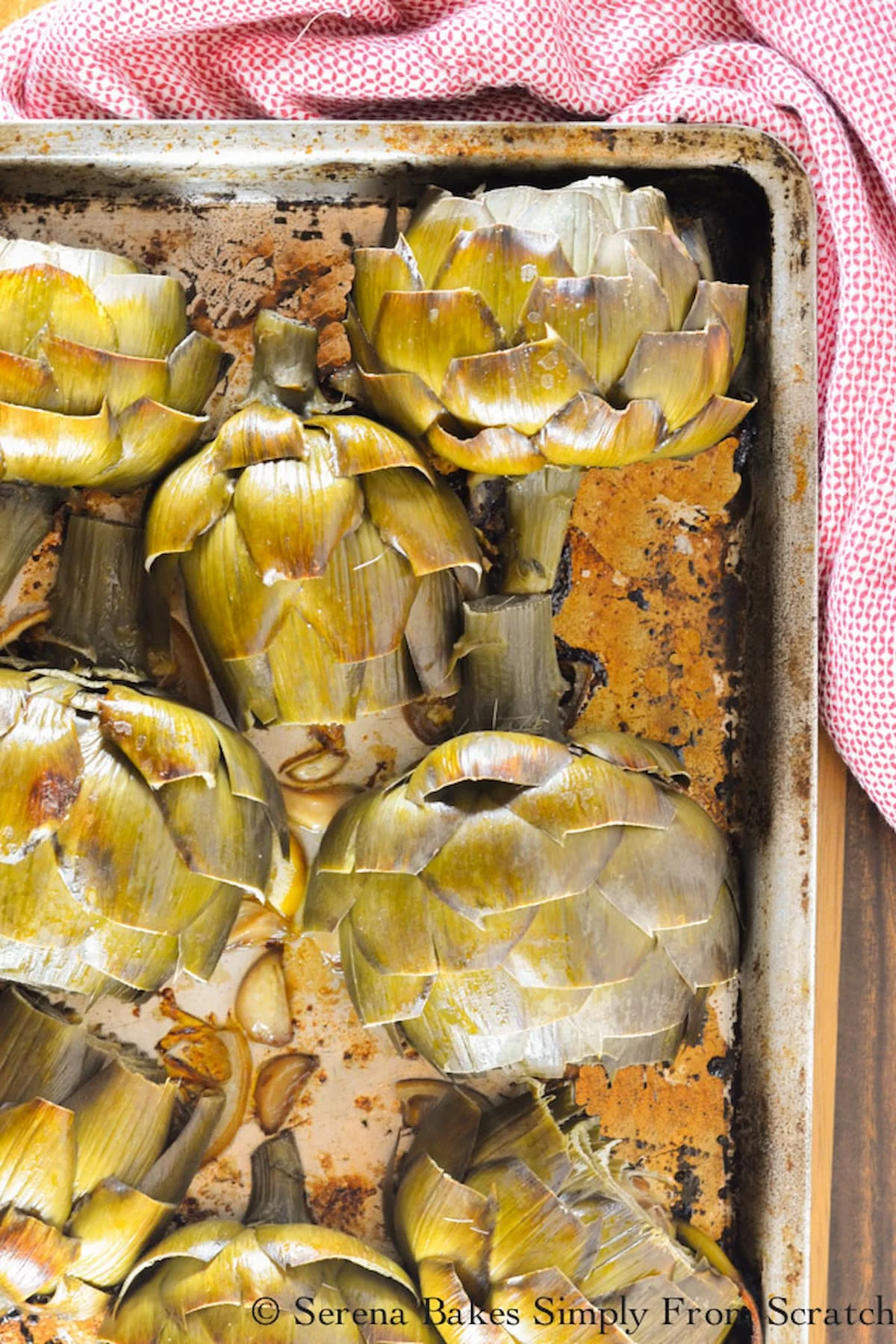 Roasted Artichokes with garlic sprinkled on baking sheet.