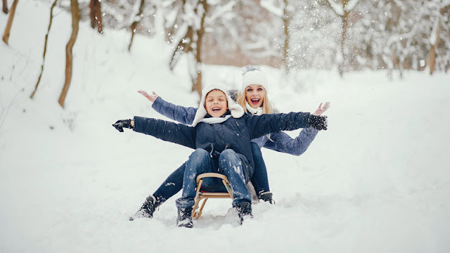 a mother and son smiling and sharing a sled