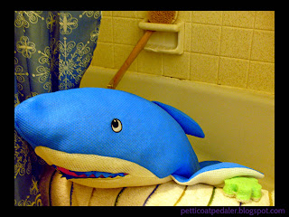 [Image Description] Photo of a blue shark pool toy set up in a bath tub to look like they are going to bath. Photo bordered in black.