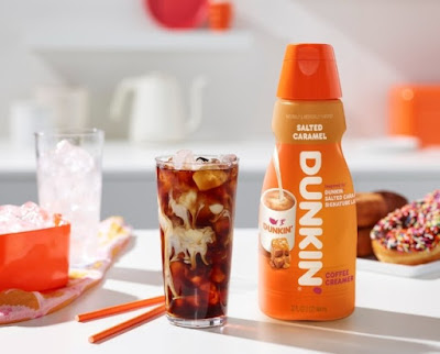 A bottle of Dunkin' Salted Caramel Creamer next to a glass of iced coffee.