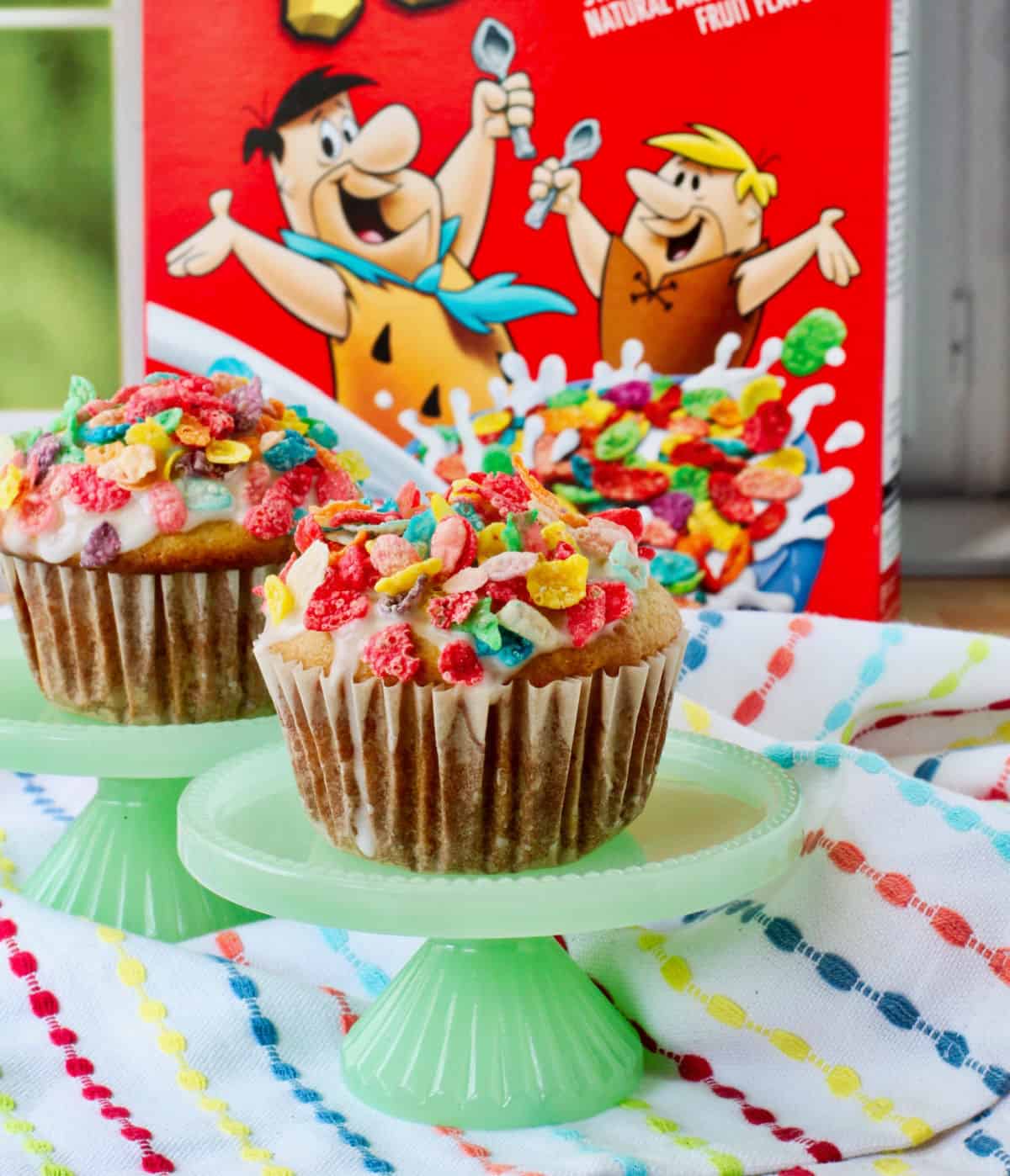 Cereal Milk Muffins with a box of Fruity Pebbles in the background.