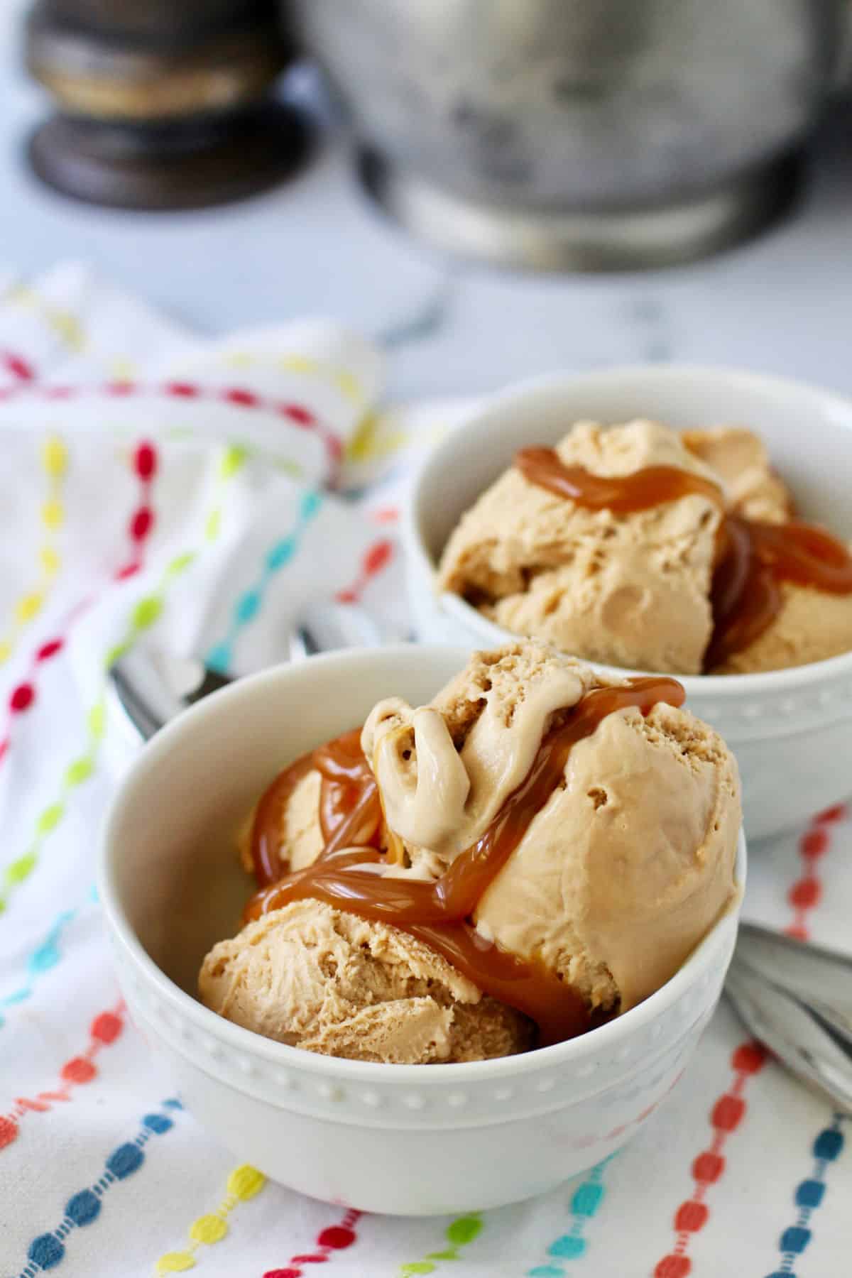 Coffee ice cream in two white bowls topped with caramel sauce.
