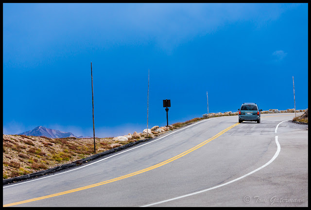 A minivan drives up Trail Ridge Road as storm clouds begin form over the mountains.