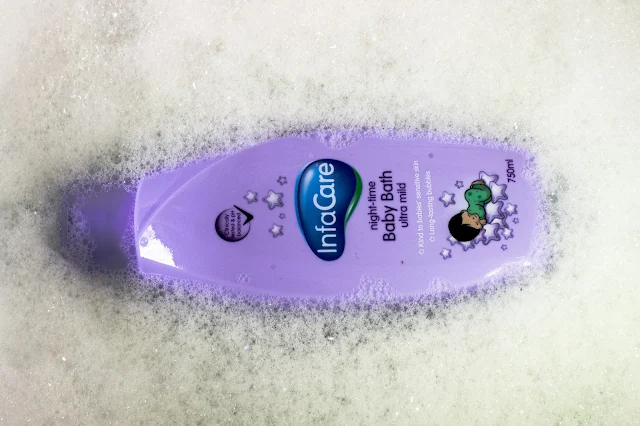 A 750ml bottle of InfaCare night time baby bath ultra mild surrounded by bubbles