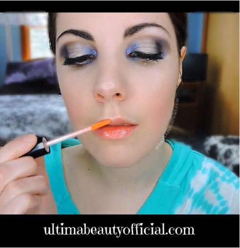 Ultima Beauty applying peach lip gloss to lips.