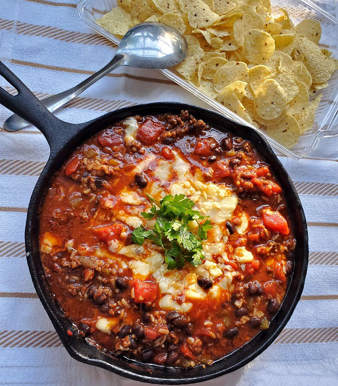 a delicious one pan skillet with beef, rice and beans topped with cheese