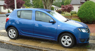 A shiny new Dacia Sandero on the driveway to the right  