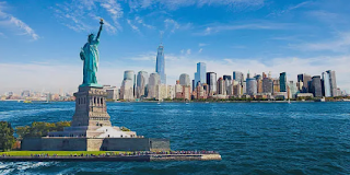 Statue of Liberty and New York City skyline viewed from the water on a clear day.