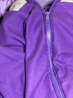 A purple jacket with a purple zipper and a grey collar.