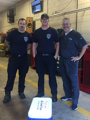 Dr. Kitzmiller stands with 2 fireman at Firestation 1.