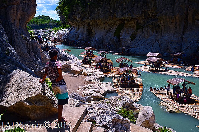 A man leaning on the rock enjoying the view of the river
