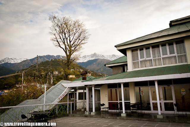 During beginning of this year, I visited Dharmshala for covering finals of Cricket Mahasangram and HPCA(Himachal Pradesh Cricket Association) had arranged for stay in Dhauladhar Hotel, which is just in the middle of Dharmshala Market.This is a view of backside where Dhauladhar Hotel has some open dining area with wonderful view to the valley !!I took Volvo form Delhi and reached early in morning. Dhauladhar Hotel is at walkable distance from Bus stand but since I had more stuff to carry, so got a taxi at very reasonable tariff (50 Rs :) )I entered into the room and it was decent, although very old. Personally I am not very choosy unless things are not neat and well placed. So I found this room a good place to stay for me. Service was also good, although I had an extra advantage of being able to speak in Himachali ! I loved the woodwork there. I have heard of Kangra Suite in this hotel which is considered as best place.Here is a view of some colony from open dining area of Dhauladhar Hotel in Dharmshala !!! This hotel is approximately 4 kilometers far from Cricket Stadium constructed by Himachal Pradesh Cricket Association.Another view of a valley from Dhauladhar Hotel in Dharmshala, Himachal Pradesh, INDIA. Usually people prefer to stay in Mcleodganj as compared to Dharmshala Town.Hotel corridor which connect most of the rooms on second floor. The first suite on the right is Kangra Suite !!!This is back side of Dhauladhar Hotel in Dharmshala ! This could have been better maintained. There is enough space to make a garden as well !!!Another view of a valley from Restaurant of Dhauladhar Hotel in Dharmshala !!!Dhualadhar Mountain ranges are clearly visible from this hotel and people prefer to have their meals in open dining area !!!This is restaurant of Dhauladhar Hotel, which can be seen empty most of the times. It's not that people don't visit, but people prefer to sit in open dining area.There is a small parking area in front of main entry of Dhauladhar hotel, but it seems currently residents of Dharmshala use it in better way :)Here is another corridor in Dhauladhar Hotel, Dharmshala. Monkeys can be seen in these corridors as whole area is not very well closed. So they enjoy walking inside this hotel to see different types of tourists !!! Soon after checking in at Dhauladhar, I had to reach stadium. I thought of walking down to the stadium and few gentlemen offered me lift but I wanted to see other things on the way. Photograph above shows dense Dharmshala town where everyone want to live !!!A photograph of road going down towards HPCA cricket stadium. Dharmshala market is mainly spread around this road only. There are some main offices are also on the way to stadium !!!Another view of Dharmshala valley full of colorful houses !!!Another HPTDC hotel in Dharmshala Market !!Roads are really well maintained inside the town. Overall roads in Himachal Pradesh are far better than what we daily see in Noida.Here is last colorful photograph from Dharmshala !!! Overall stay at Dhauladhar Hotel was good and I love HPTDChotel.