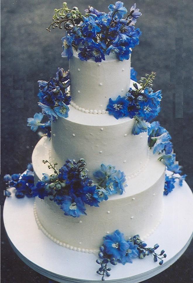 Three tier white wedding cake with edible pearl decorations and bright blue 