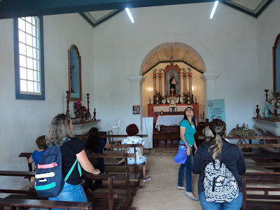 Pessoas rezando dentro da igreja, ao fundo o altar