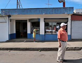 woman on sidewalk and man in middle of road in Puriscal