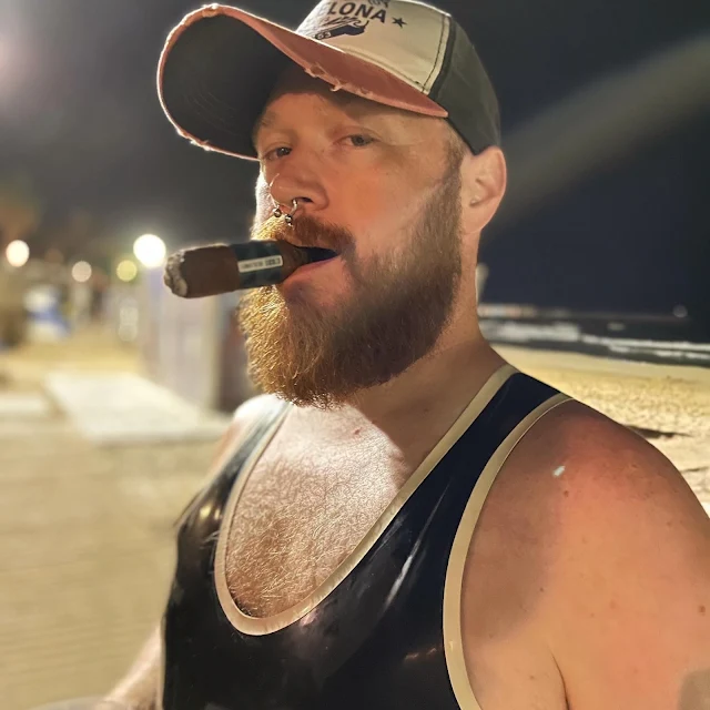 Handsome blonde burly bearded daddy smoking a cigar outside from chest up