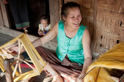 This Lao village artisan, whose silk work supplements her subsistence farming activities, twists the silk yarns to condition and strengthen them prior to weaving.