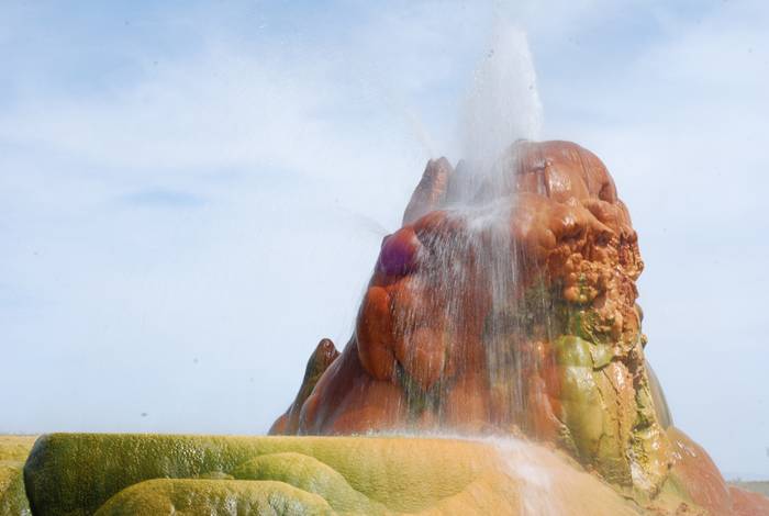 Fly Geyser is a little-known tourist attraction, even to Nevada residents. It is located near the edge of Fly Reservoir and is only about 5 feet (1.5 m) high, (12 feet (3.7 m) counting the mound on which it sits). The Geyser is not an entirely natural phenomenon, and was accidentally created in 1916 during well drilling. The well functioned normally for several decades, but in the 1960s geothermally heated water found a weak spot in the wall and began escaping to the surface. Dissolved minerals started rising and accumulating, creating the mount on which the geyser sits, which continues growing. Today water is constantly spewing, reaching 5 feet (1.5 m) in the air. The geyser contains several terraces discharging water into 30 to 40 pools over an area of 30 hectares (74 acres). The geyser is made up of a series of different minerals, which gives it its magnificent coloration.