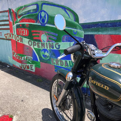 Motorcycle in front of mural of train engine.