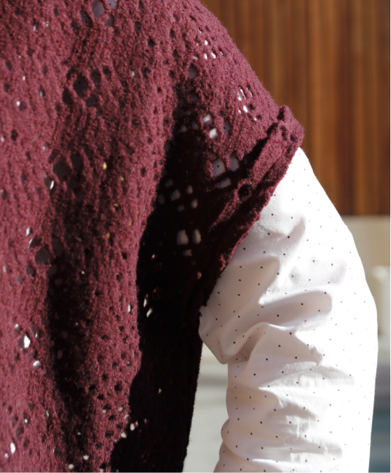 a close up shot of the sleeve of a plum wool vest and a white shirt