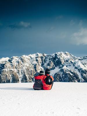 Couple sitting down on a date looking at a snow mountain