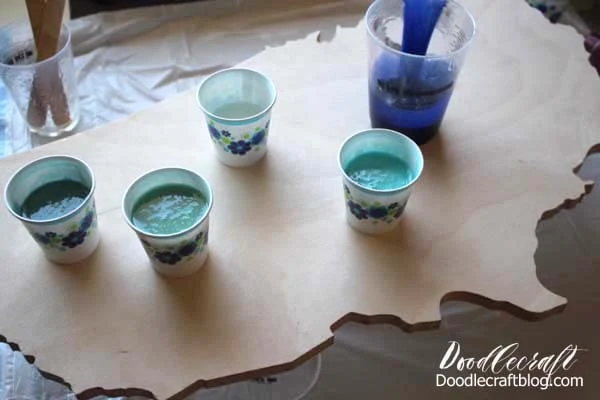 Mixing the paint into the resin for an Ocean Resin Pour on USA Cutout DIY tutorial to make home decor look like the waves of the ocean in ombre shades of blue.